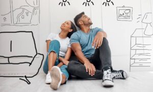 A young couple sitting on the floor with sketches of possible home customizations around them thinking about improvements.