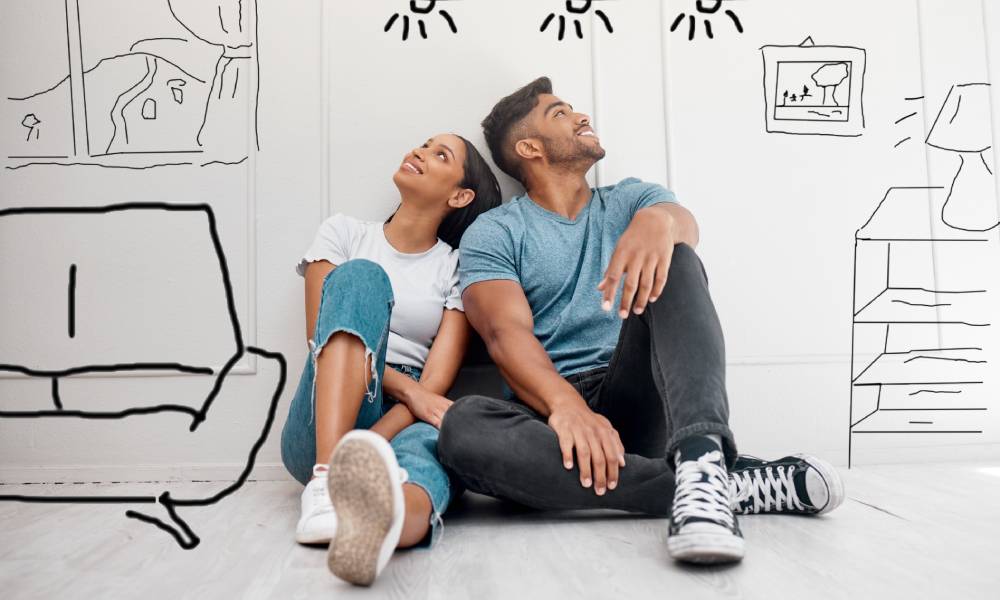 A young couple sitting on the floor with sketches of possible home customizations around them thinking about improvements.