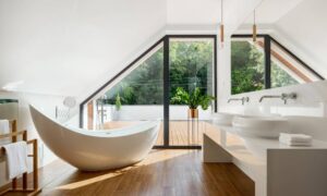 A clean, airy bathroom with a freestanding bathtub and a floor-to-ceiling window leading to a deck or patio.