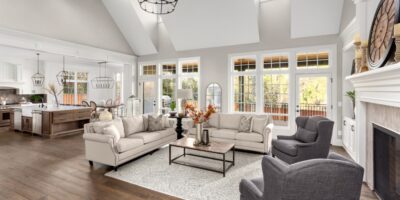 An opulent-looking living room showcasing two couches and two chairs in front of large windows and next to a fireplace.