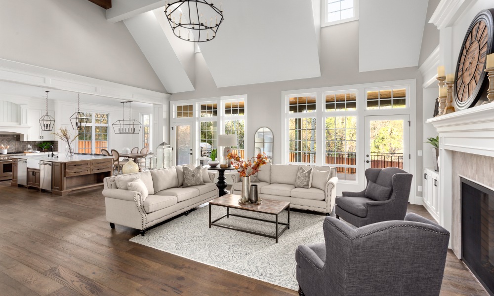 An opulent-looking living room showcasing two couches and two chairs in front of large windows and next to a fireplace.