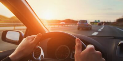 Someone driving a vehicle on the highway in the right hand lane. They have two hands on the steering wheel.