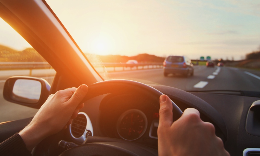 Someone driving a vehicle on the highway in the right hand lane. They have two hands on the steering wheel.