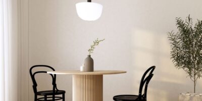 A breakfast nook with a round wooden dining table and black chairs. There's a pendent light hanging over the table.