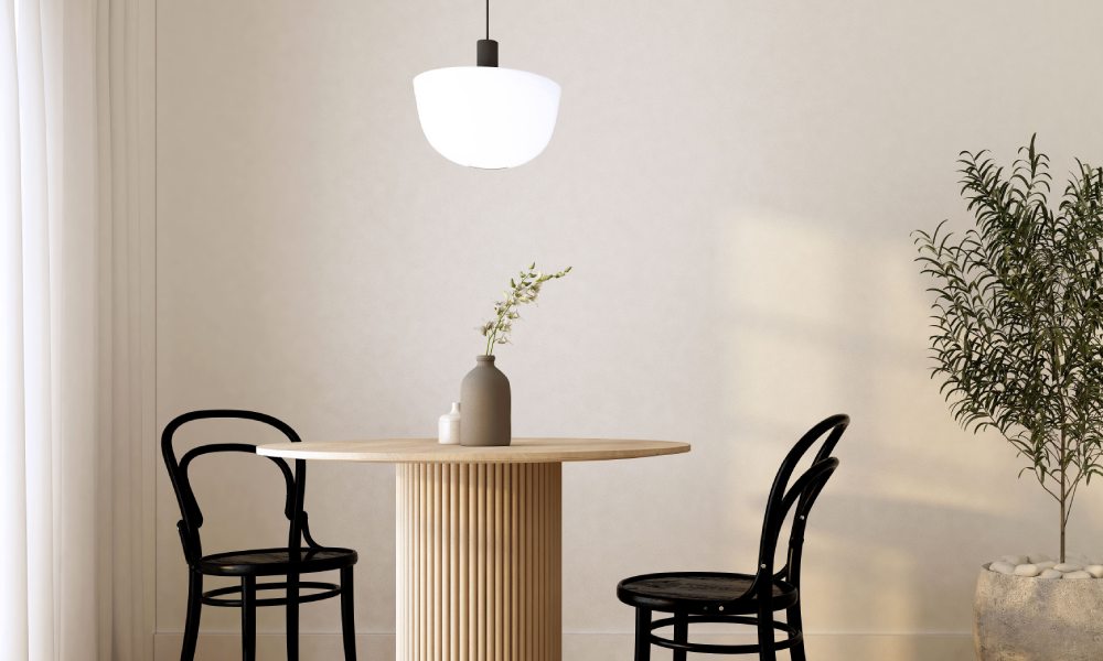 A breakfast nook with a round wooden dining table and black chairs. There's a pendent light hanging over the table.