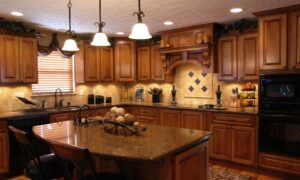 An expensive-looking Tuscan-style kitchen with dark cabinets and countertops, black appliances, and an intricate tile backsplash.