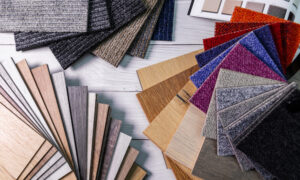 An assortment of colorful laminate and carpet flooring samples displayed across a gray wooden floor.