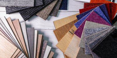 An assortment of colorful laminate and carpet flooring samples displayed across a gray wooden floor.