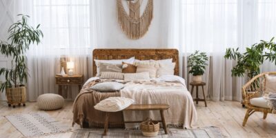 The interior of a rustic bedroom with wood floors and decorations plus a bed with a comforter and several pillows.