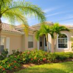 On a bright, sunny day, a home is nestled in a peaceful yard with lush, tropical trees and a green garden.