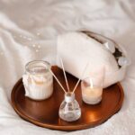 home scent and a reed diffuser, on a metallic plate. The plate is on a white sheet.