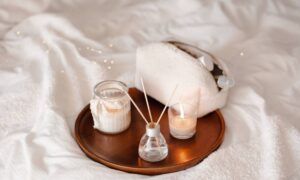 home scent and a reed diffuser, on a metallic plate. The plate is on a white sheet.