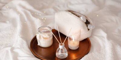 home scent and a reed diffuser, on a metallic plate. The plate is on a white sheet.